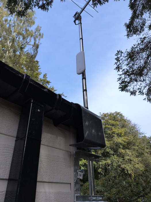 Wireless link radio on a mast beside a building at Forest Park, with trees behind
