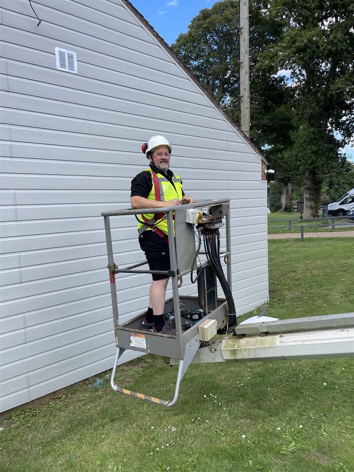 Netcom engineer working from an access platform beside a holiday home